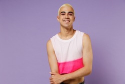 Young blond cool fun latin gay man 20s with make up wearing fashionable bright pink top look camera isolated on plain pastel purple background studio portrait. People lifestyle fashion lgbtq concept