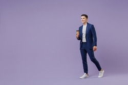 Full size young successful employee business man lawyer 20s wear formal blue suit white t-shirt hold takeaway paper brown cup coffee go look aside isolated on pastel purple background studio portrait