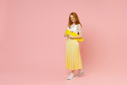 Full length body young smiling redhead energetic ginger teenager student caucasian woman 20s wear glasses summer clothes maxi skirt hold skateboard isolated on pastel pink background studio portrait