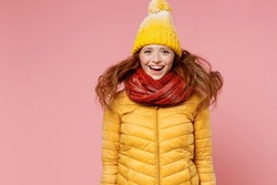 Surprised pop-eyed young woman 20s years old wears yellow jacket hat mittens jumping keep mouth wide open have fun enjoy fluttering hair isolated on plain pastel light pink background studio portrait