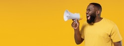Young black man 20s wearing bright casual t-shirt hold scream shout in megaphone announces discounts sale Hurry up isolated on plain yellow color background studio portrait. People lifestyle concept