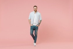Full length young happy cheerful friendly caucasian unshaven man 20s in blue striped shirt white t-shirt look camera isolated on pastel pink color background studio portrait. People lifestyle concept