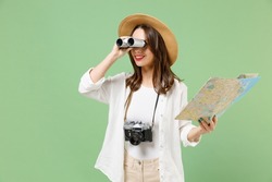 Traveler smiling exploring tourist woman in casual clothes hat hold paper map look through binoculars isolated on green background Passenger travel abroad weekends getaway Air flight journey concept.