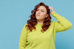 Young puzzled thoughtful confused chubby overweight plus size big fat fit woman wear green sweater look aside scratch head isolated on plain blue background studio portrait. People lifestyle concept