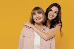 Two young smiling satisfied daughter mother together couple women wearing casual beige clothes looking camera hug isolated on plain yellow color background studio portrait. Family lifestyle concept