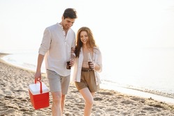 Happy young couple two friend family man woman in white clothes hold beer bottle bag refrigerator have picnic rest together at sunrise over sea beach ocean outdoor seaside in summer day sunset evening