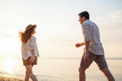 Back rear view young fun couple two friends family man woman in white shirt clothes hold hands walk run stroll together at sunrise over sea beach ocean outdoor exotic seaside in summer day evening.
