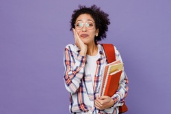 Young happy excited girl woman of African American ethnicity teen student in shirt backpack hold books face isolated on plain purple background. Education in high school university college concept.