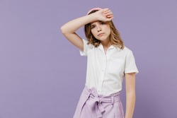 Little sad tired sick exhausted blonde kid girl 12-13 years old in white shirt put hand on forehead have headache isolated on purple background children studio portrait. Childhood lifestyle concept