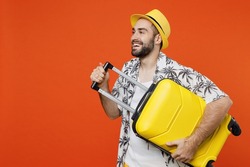 Traveler tourist fun man wear summer casual clothes hat hold suitcase bag look aside isolated on plain orange background studio. Passenger travel abroad on weekends getaway. Air flight journey concept