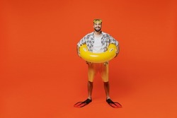 Full body smiling young tourist man in beach shirt goggles hold inflatable ring flippers travel abroad on weekends isolated on plain orange background studio Summer vacation sea rest sun tan concept