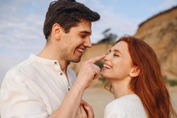 Side view close up smiling happy young lovely couple two friend family man woman in casual clothes touch girlfriend nose forehead at sunrise over sea beach outdoor seaside in summer day sunset evening