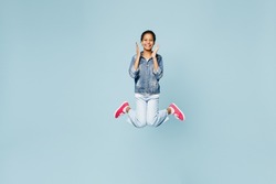 Full body excited exultant happy little kid teen girl of African American ethnicity 12-13 year old in denim jacket jump high hold face isolated on pastel plain light blue background. Childhood concept
