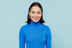 Smiling fancy fascinating young woman of Asian ethnicity 20s years old wears blue shirt looking camera isolated on plain pastel light blue background studio portrait. People emotions lifestyle concept