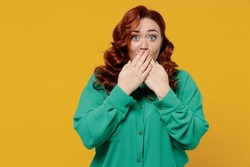 Secret bright vivid young ginger chubby overweight woman 20s years old wears green shirt cover mouth with hand isolated on plain yellow background studio portrait. People emotions lifestyle concept