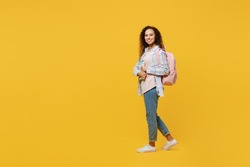 Full body side view happy young black teen girl student she wear casual clothes backpack bag hold books walking going isolated on plain yellow color background. High school university college concept