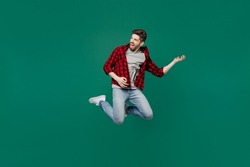 Full body young happy expressive singer caucasian man he 20s wearing red shirt grey t-shirt play guitar rock musician isolated on plain dark green background studio portrait. People lifestyle concept