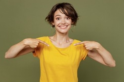 Young smiling lucky happy woman she 20s wear yellow t-shirt confident woman pointing index fingers on herself isolated on plain olive green khaki background studio portrait. People lifestyle concept