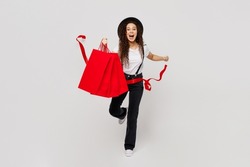 Full body young woman wear t-shirt hat hold in hand paper package bags after shopping run cross red finish ribbon celebrate isolated on plain solid white background. Black Friday sale buy day concept