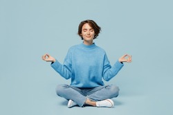 Full body young woman wear knitted sweater holding spreading hands in yoga om aum gesture relax meditate try to calm downisolated on plain pastel light blue cyan background. People lifestyle concept