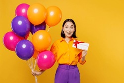 Happy fun young woman wears casual clothes celebrating hold bunch of balloons gift certificate coupon voucher card for store isolated on plain yellow background. Birthday 8 14 holiday party concept