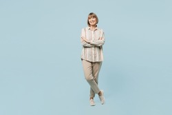 Full body smiling happy fun elderly woman 50s years old wear shirt hola hands crossed folded look camera isolated on plain pastel light blue cyan color background studio portrait. Lifestyle concept