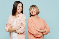 Smiling fun elder parent mom with young adult daughter two women together wearing casual clothes hold hands crossed folded look to each other isolated on plain blue cyan background. Family day concept