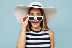 Young surprised impressed woman she wearing striped tank shirt casual clothes hat lower sunglasses look camera isolated on plain pastel light blue cyan background studio portrait. Lifestyle concept