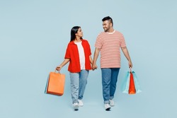 Full body young couple two friend family Indian man woman wear red casual clothes hold package bags after shopping go isolated on plain blue color background studio. Black Friday sale buy day concept