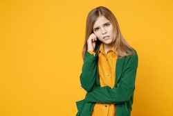 Little blonde kid pensive girl 12-13 years old wearing casual clothes green shirt show prop up forehead look camera isolated on yellow orange background children studio. Childhood lifestyle concept