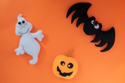 cute halloween concept. hand made kids toy. pumpkin head, ghost, bat on orange background. top view