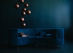livingroom with blue velvet sofa. golden and blue pillows. sphere bronze lamps. modern interior in blue tones.