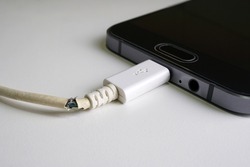 Old charger cable broken and smartphone, Defective charging cord, Connection deterioration device