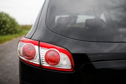 Back view of new black car. Closeup headlights of car. Black premium city crossover, luxury SUV rear light closeup. Car lamp close-up.