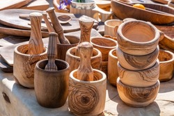 Brown Wooden kitchen utensils at outdoor street market stall. Side view on wood handmade kitchenware, cups, bowls, mortar. Zero waste, Eco-friendly concept. Sun light falling on objects. cıopy space