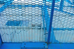 Bottom view through metal blue industrial mesh.