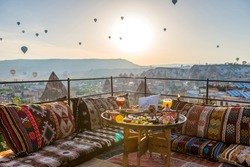 Traditional turkish breakfast with Cappadocia view and flying balloons on the background. Goreme, Turkey.