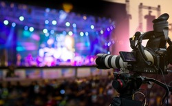 Video production covering event on stage by professional video camera in outdoor concert at sunset