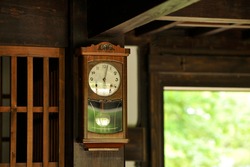 Old wall clock hung on a wooden pillar of an old Japanese house