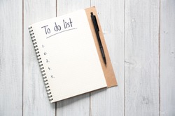 Notebook with an to do list on white wooden background and pen with copy space, planning and design concept.