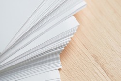 Stack of clean sheets paper, laid out randomly in wooden background. Abstract background of paper sheets