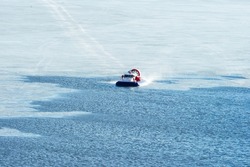 Hovercraft crossing frozen river in the sunny winter day. Transport on ice. Hovercraft, top view