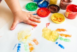 Close up of colored hand print on white background. Ideas for drawing with finger paints. Finger painting for kids. Little girl painting by finger hand paint color. Children development concept.