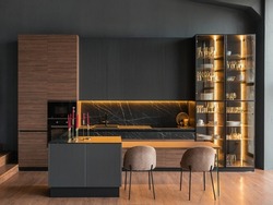 contemporary kitchen in a modern style, wooden floor, dark grey interior.  kitchen island. cabinet with glass doors and lighting for wine glasses. upholstered chairs. countertops with black cabinets