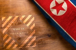 Flag of North Korea made from rough fabric on a wooden background and stamp made in North Korea