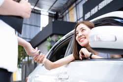 Young woman receives a key from car showroom after making car purchase contract.