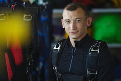 Young skydiver with a parachute is posing surrounded by parachute equipment, portrait.