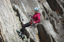 Young woman is engaged in rock climbing in the mountains. Sport climbing.