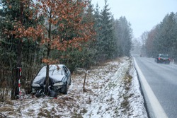 Car destroyed during the traffic accident. It was caused by the bad weather conditions in winter, because of the black ice or snow. The car is abandoned and stands by the road in the snowfall.