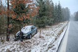 Car destroyed during the traffic accident. It was caused by the bad weather conditions in winter, because of the black ice or snow. The car is abandoned and stands by the road in the snowfall.